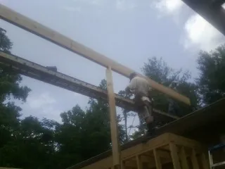 Carpenter setting a ridge beam over a new addition frame — Ice Dam Removal by Roofing Brothers in New Salem