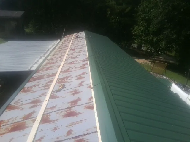 Old rusted panels beside newly installed green metal roofing — Wind Damage Roof Repair by Roofing Brothers in New Salem
