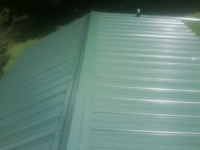 New green metal panels meeting at the ridge of a roof in New Salem