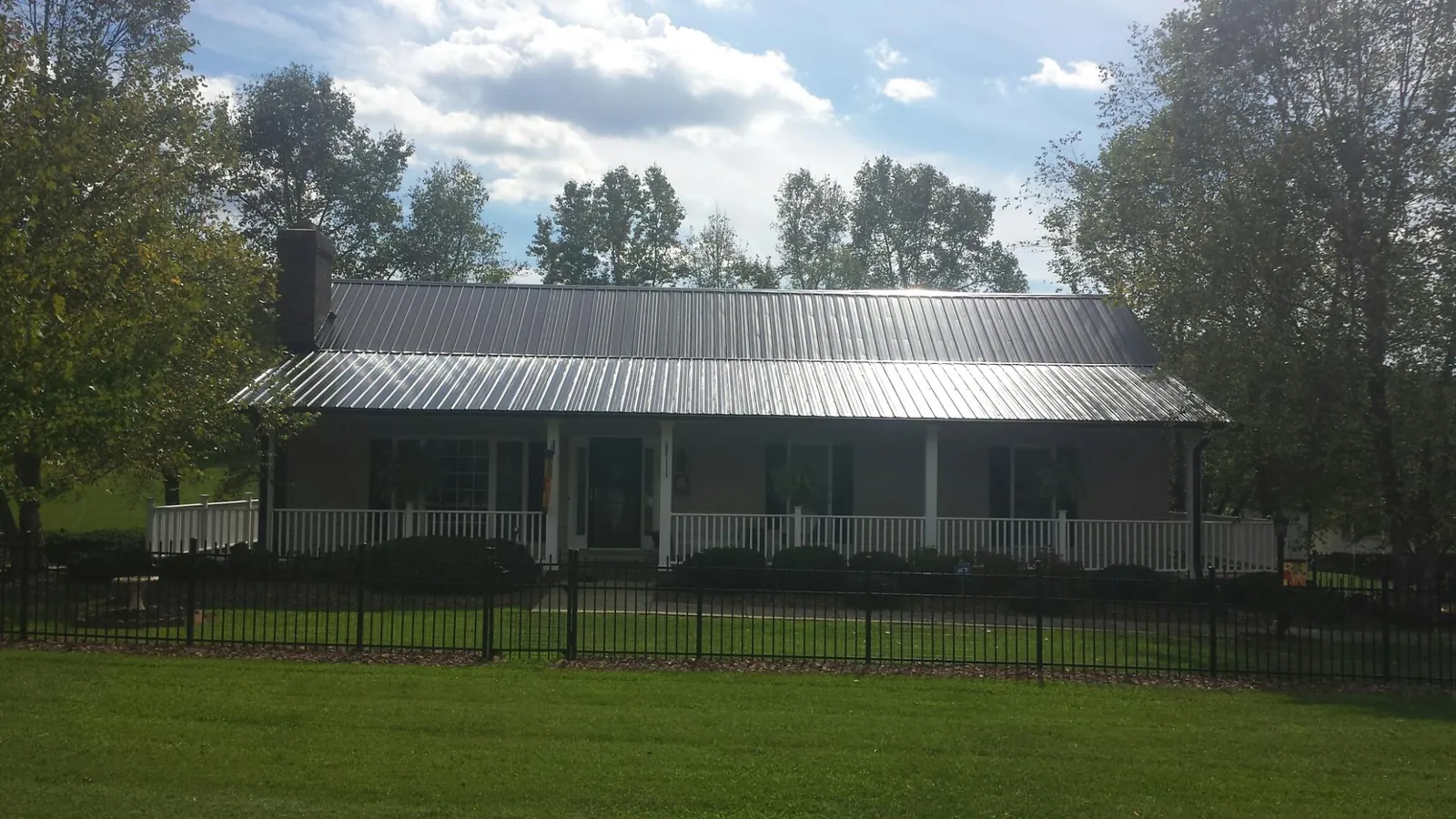 Gray metal roof on a brick ranch with a full width front porch — Gutter Guard Installation work by our crew in New Salem